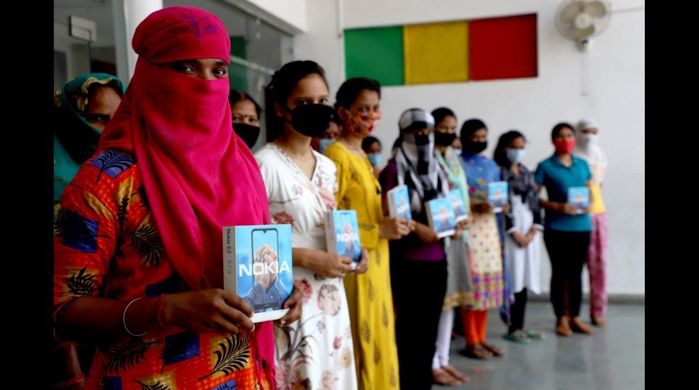 A group of women wearing face masks are standing in a line holding books.