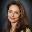 A woman with long brown hair is smiling for the camera.
