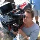 A man is sitting on the ground holding a camera.