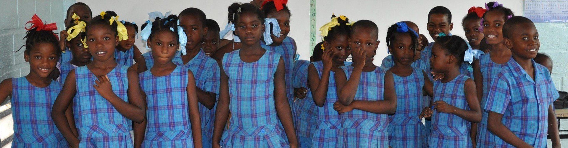 A group of children in blue dresses are posing for a picture