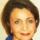 A close up of a woman 's face wearing earrings and a blue shirt.