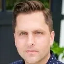 A close up of a man 's face wearing a blue shirt.