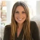 A woman with long hair is smiling and wearing a black shirt.
