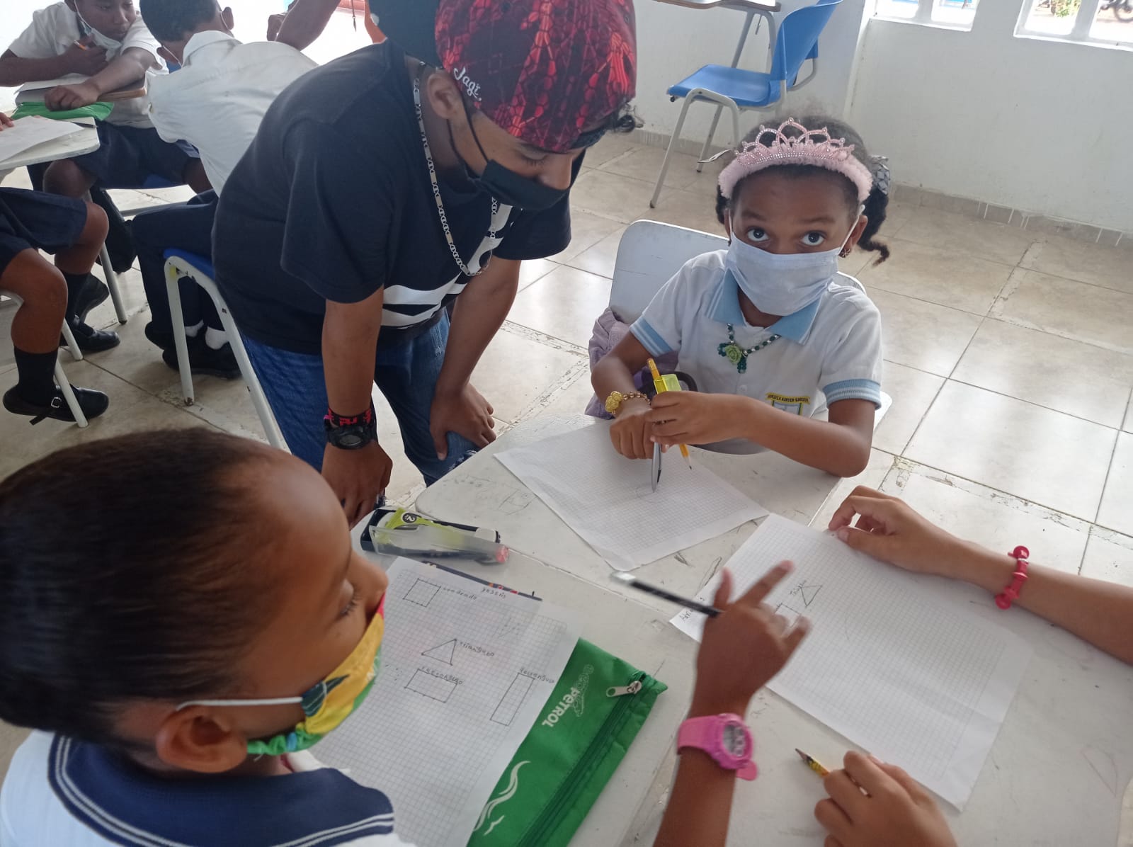 A group of children wearing face masks are sitting at a table.