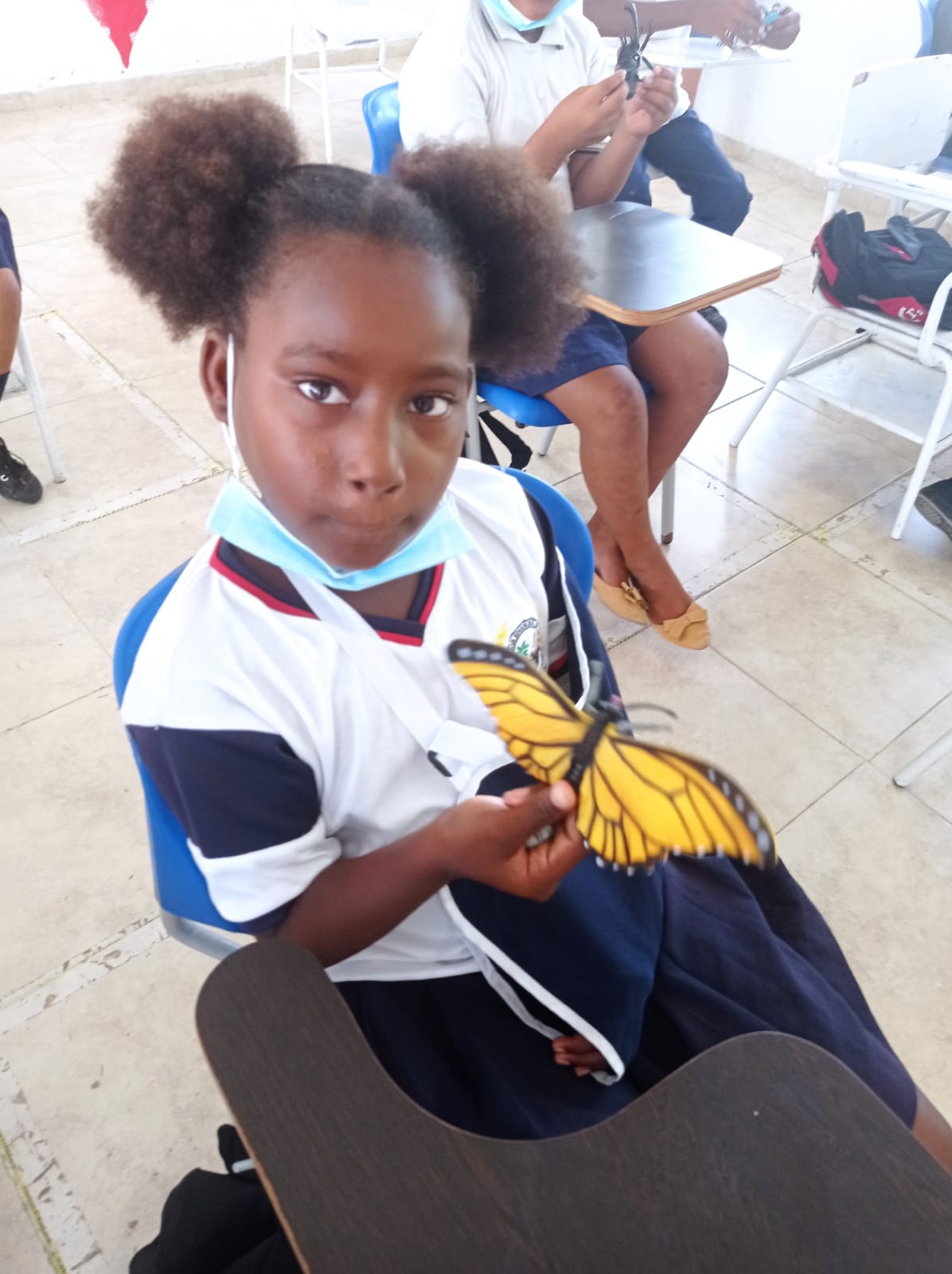 A girl wearing a mask is holding a yellow butterfly