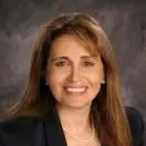 A woman in a suit and necklace is smiling for the camera.