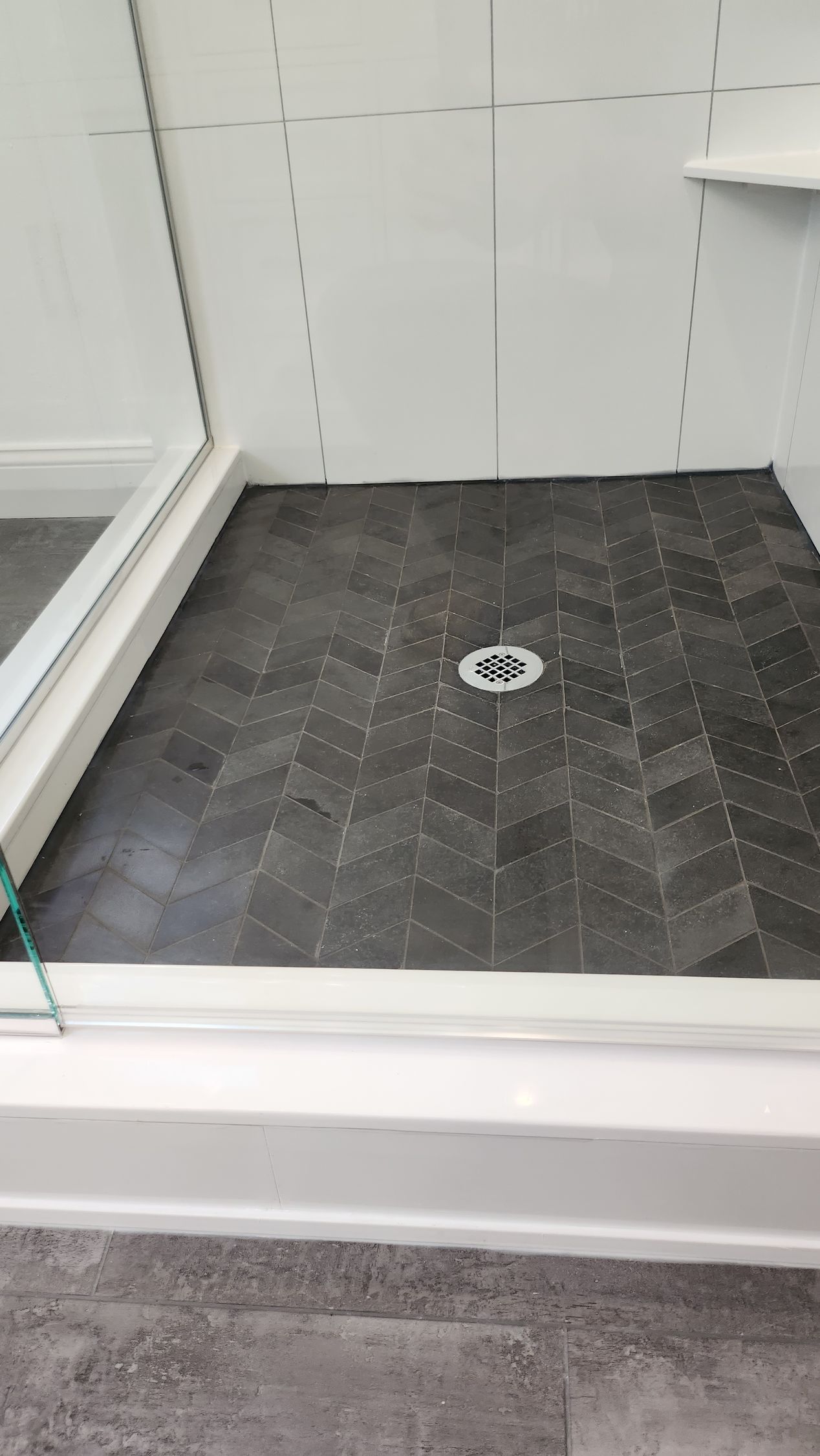 A bathroom with a black tile floor and a white shower door.