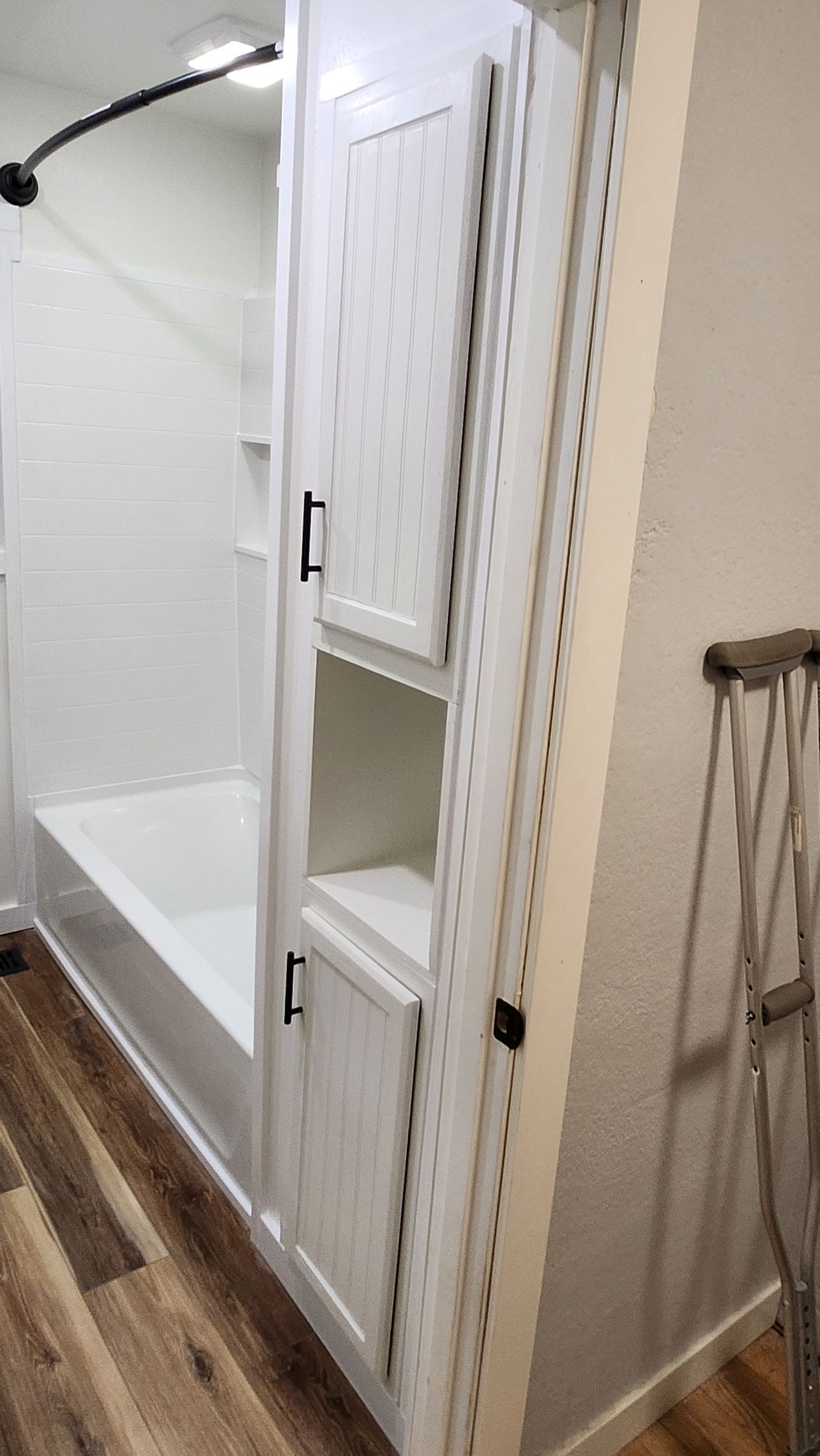 A bathroom with a bathtub , cabinets , and a ladder.