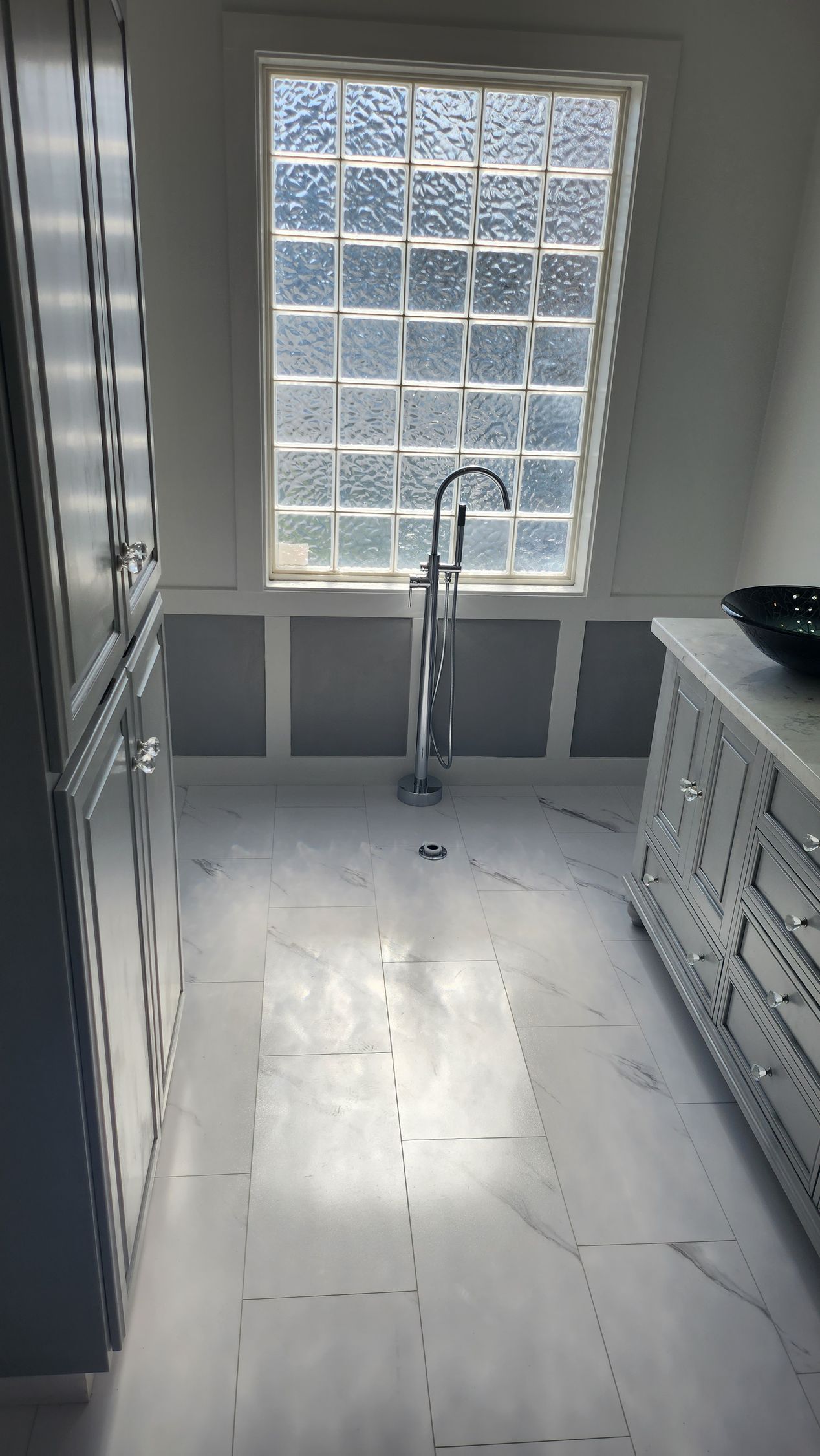A kitchen with a sink , cabinets , and a window.