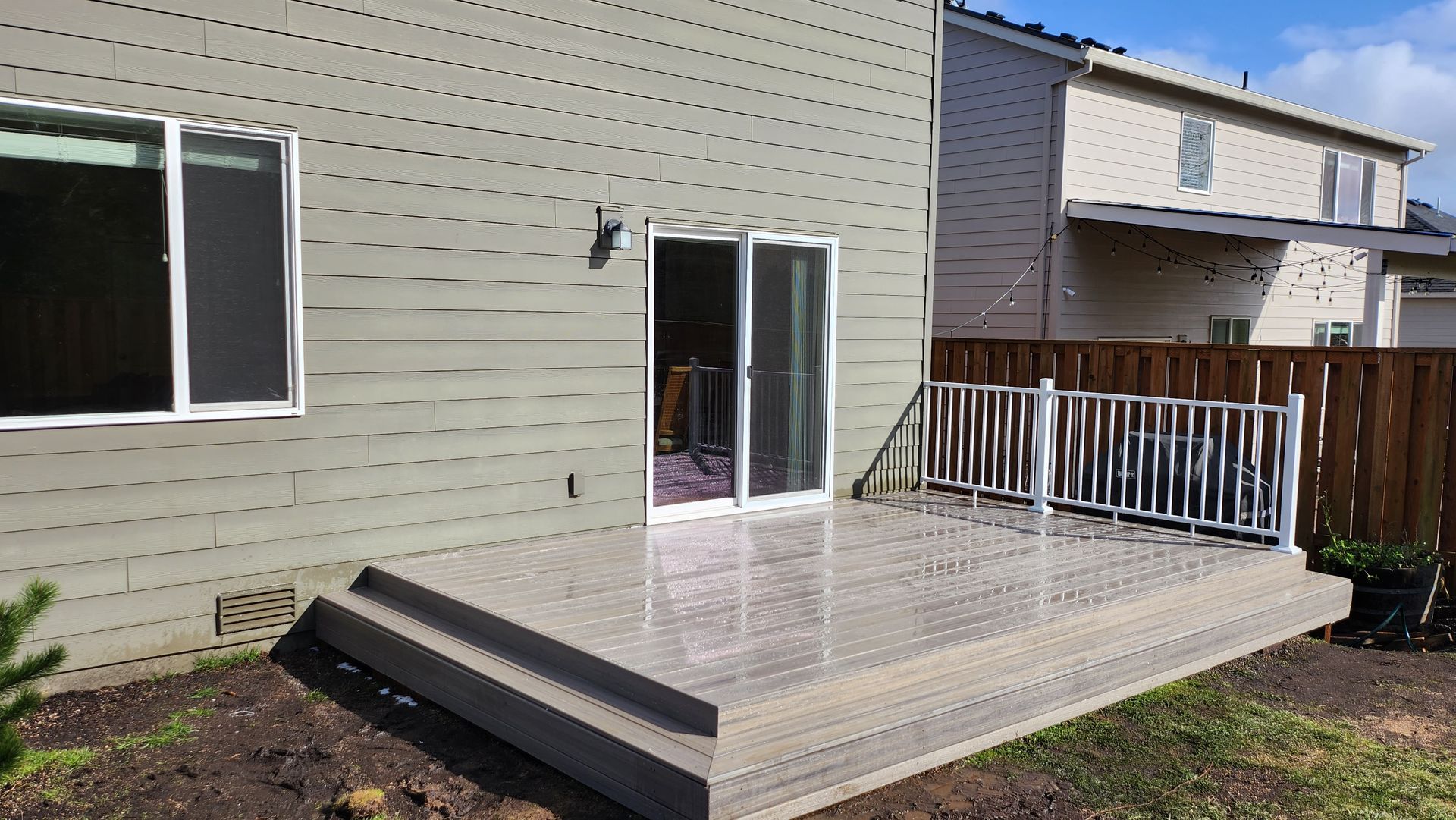 A patio with a sliding glass door in the backyard of a house.