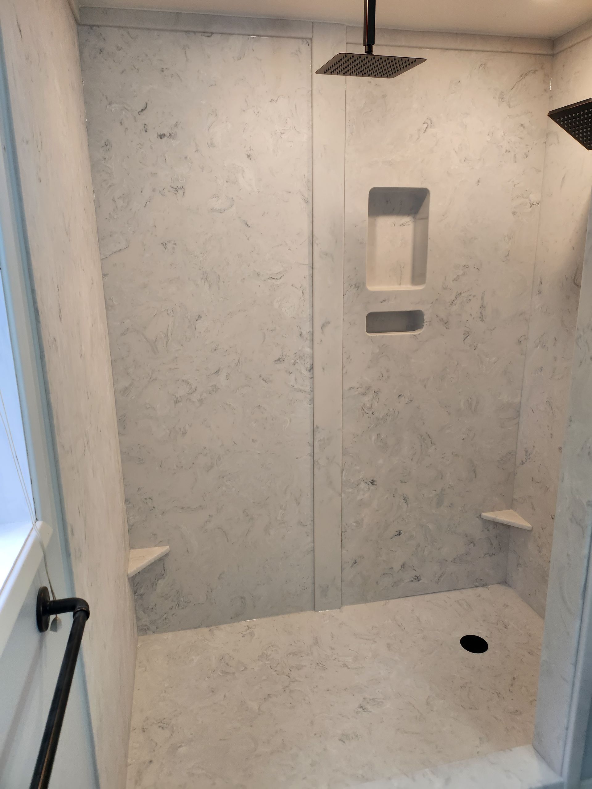 A bathroom with a walk in shower and a shower head.