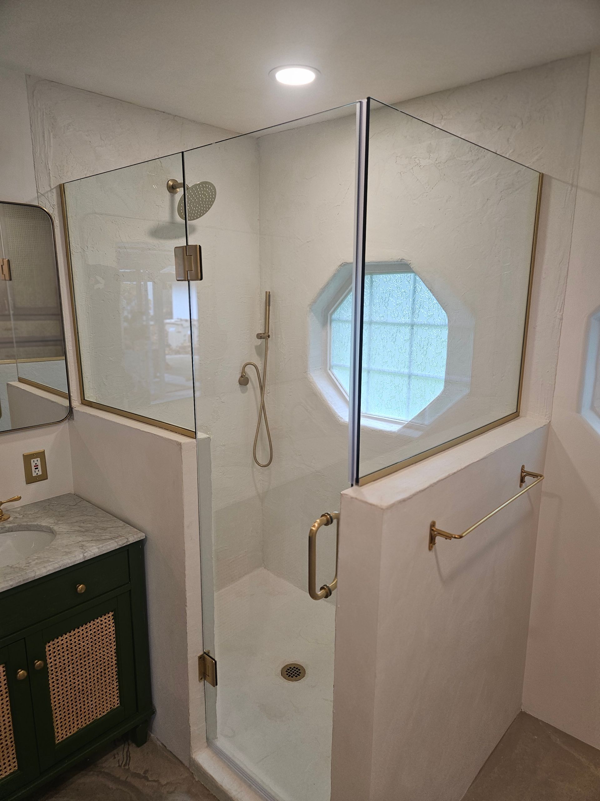 A bathroom with a walk in shower and a sink.