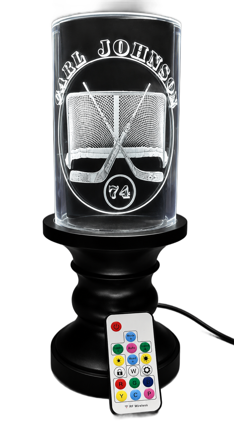 Black lamp with a lit tree design and a colorful remote control attached at the base