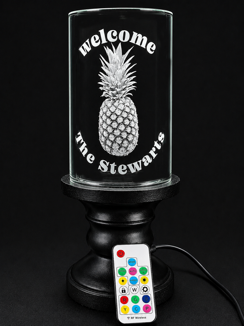 Black lamp with pineapple design and “welcome the steward” text, plus a colorful remote control.
