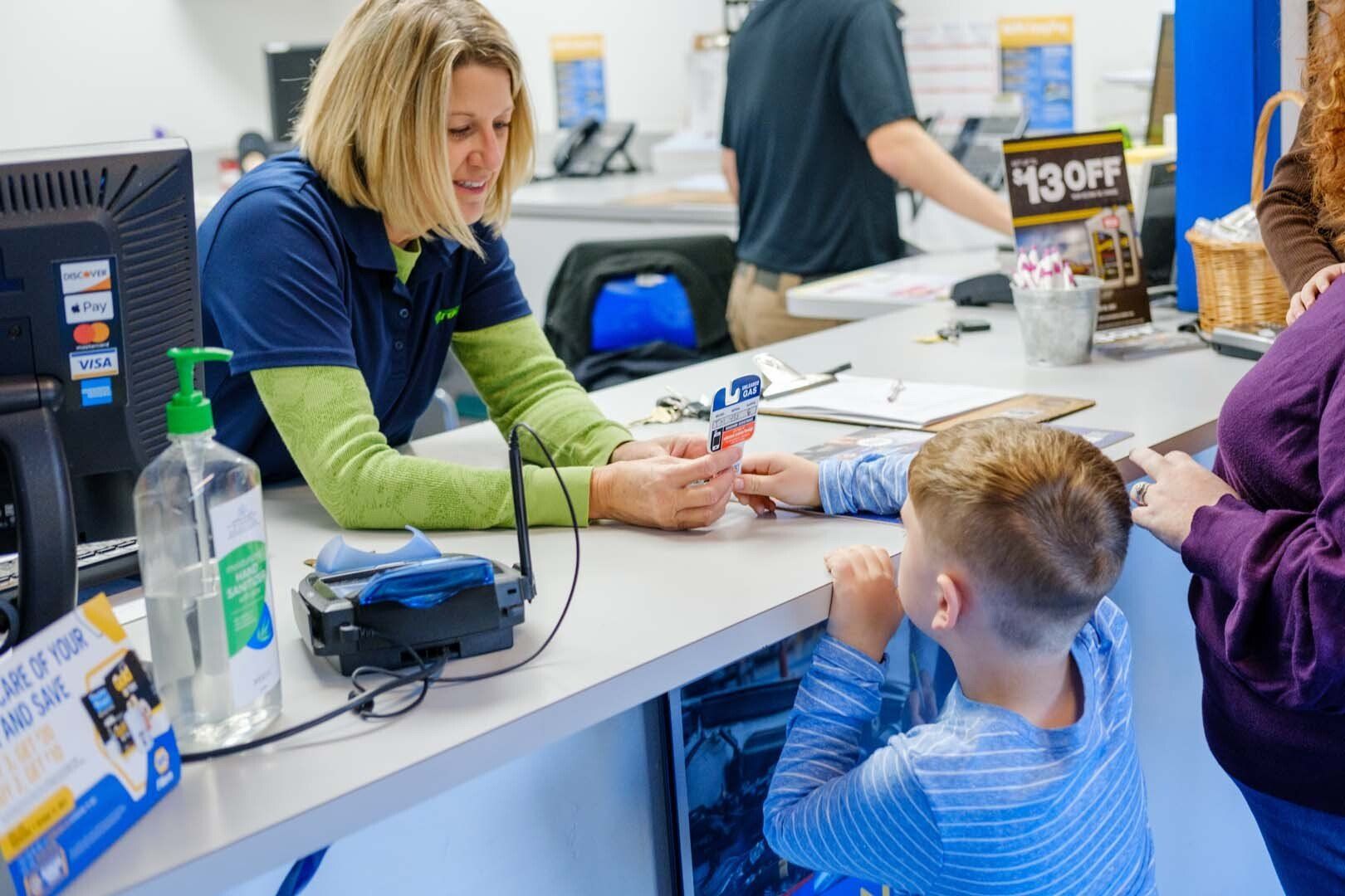 Woman helping a child at a counter, possibly in a store; hand sanitizer visible.