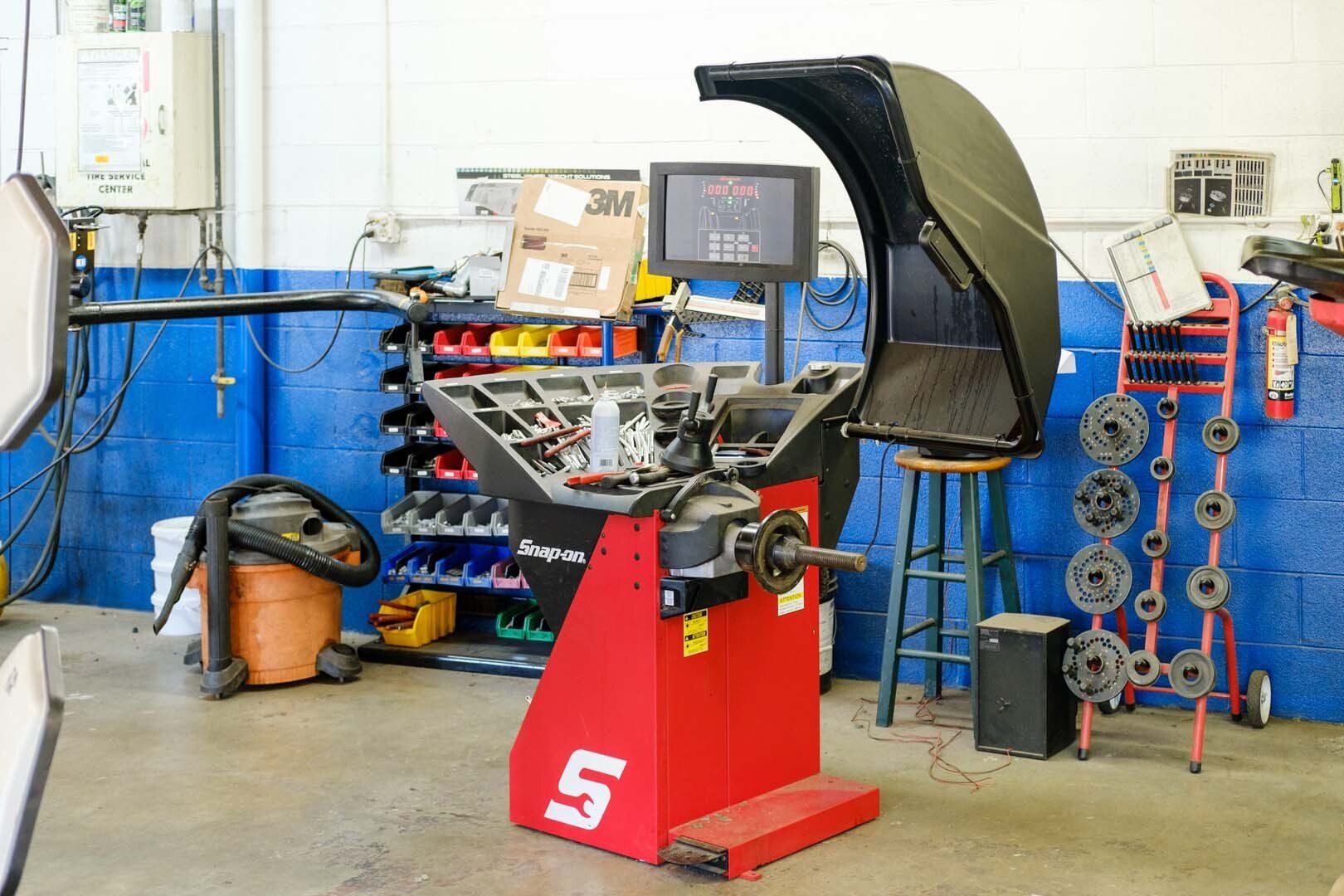 Red and black Snap-on tire balancing machine in a garage.