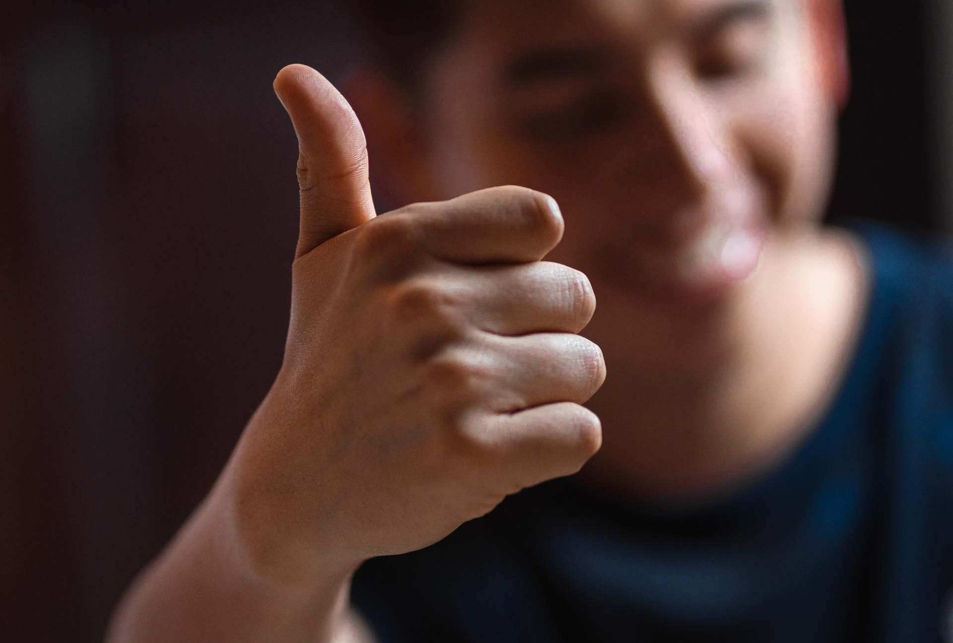 Person giving a thumbs up, smiling.