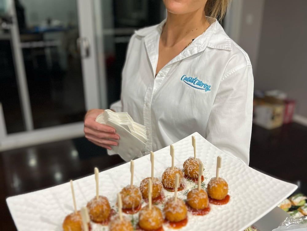 A Woman in a White Shirt is Holding a Plate of Food on Sticks — Coastal Catering in North Avoca, NSW