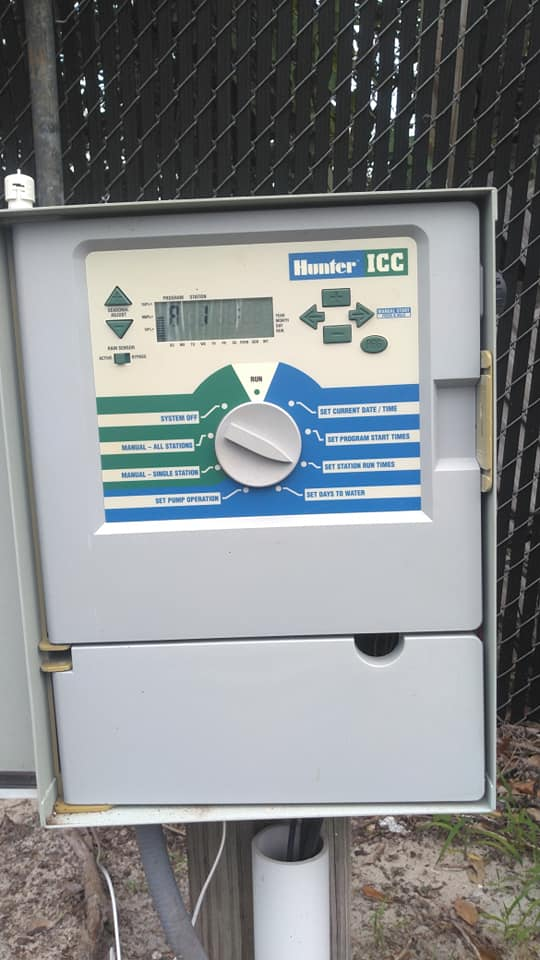 Hunter ICC irrigation controller box, outdoors. Gray box, blue and green control panel.