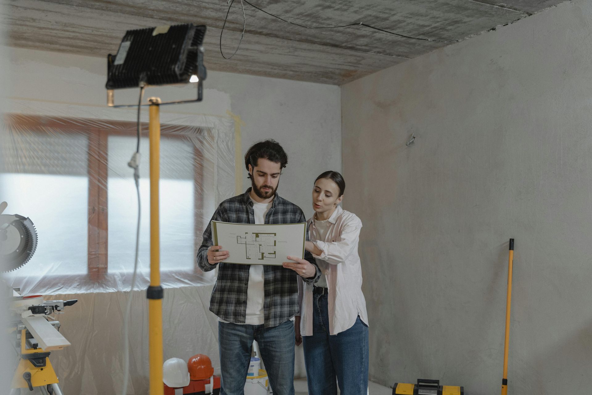 Construction and Renovation A couple reviewing a blueprint in a room undergoing significant renovation.