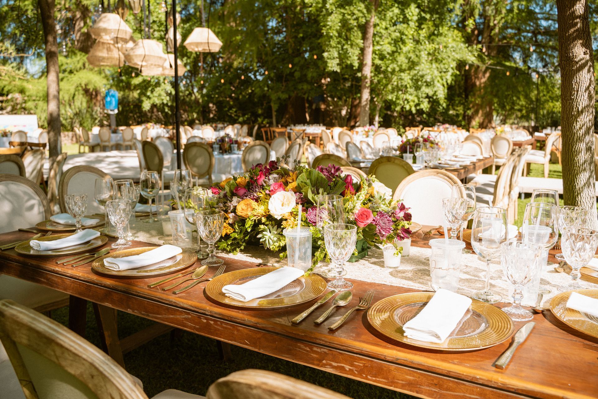 Outdoor dining table set for a formal event with floral centerpiece and place settings.