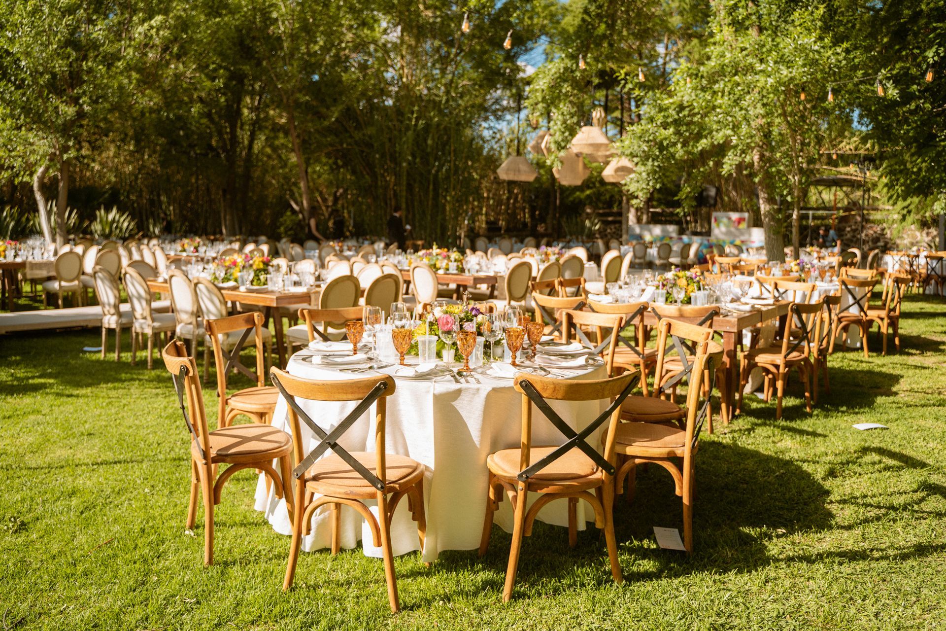 Outdoor wedding reception with round tables, chairs, and floral centerpieces.