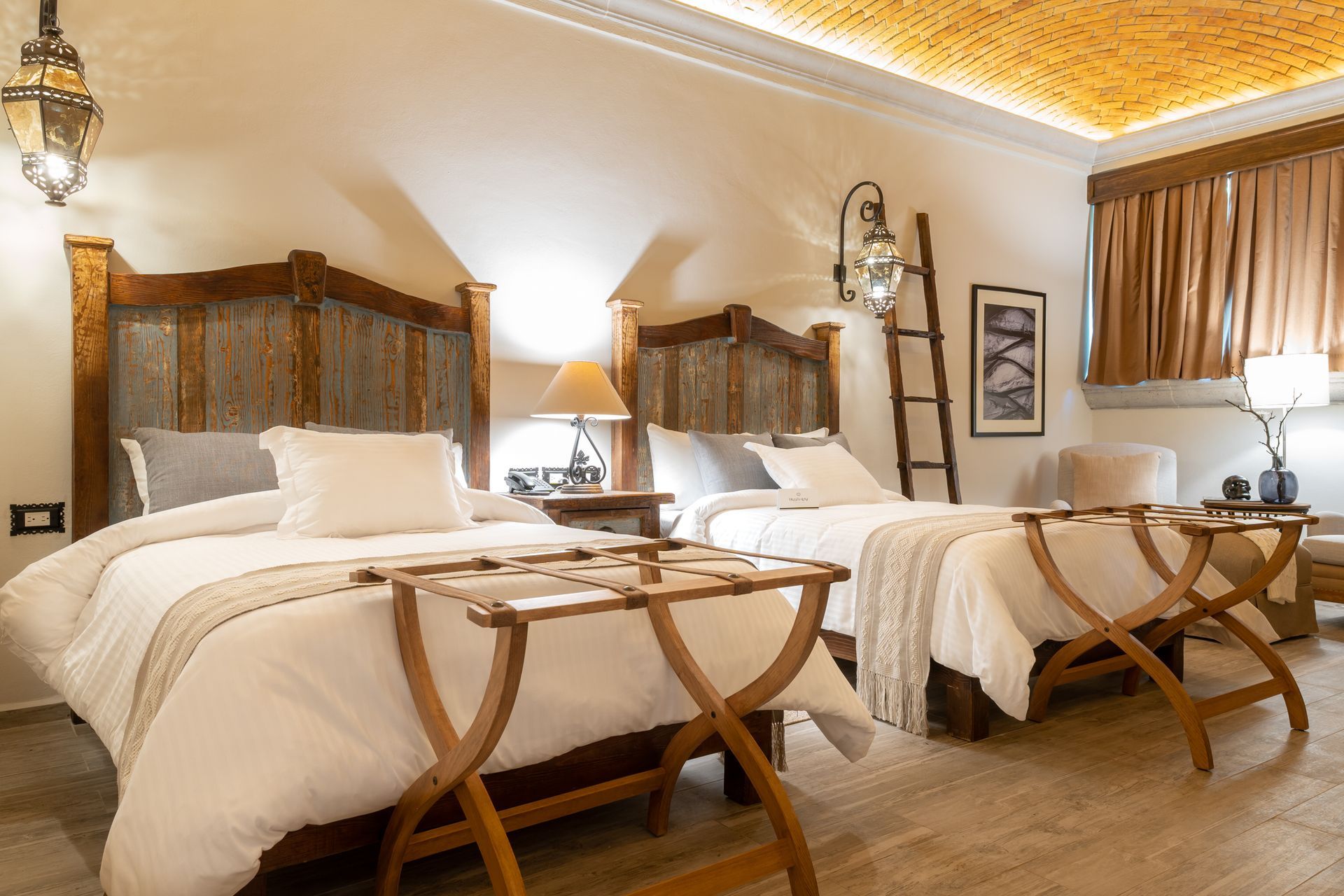 Hotel room with two beds, luggage racks, lamps, and a decorative ceiling.