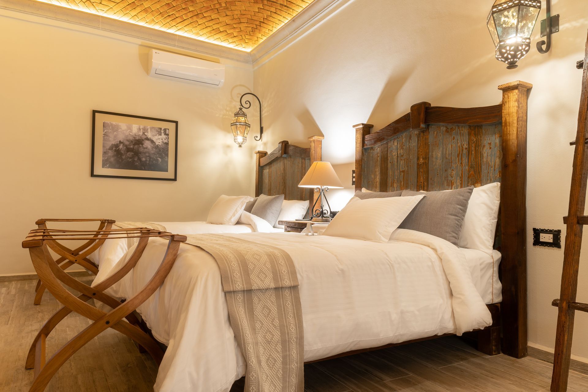Hotel bedroom with two beds, decorative wooden headboards, and ornate ceiling.