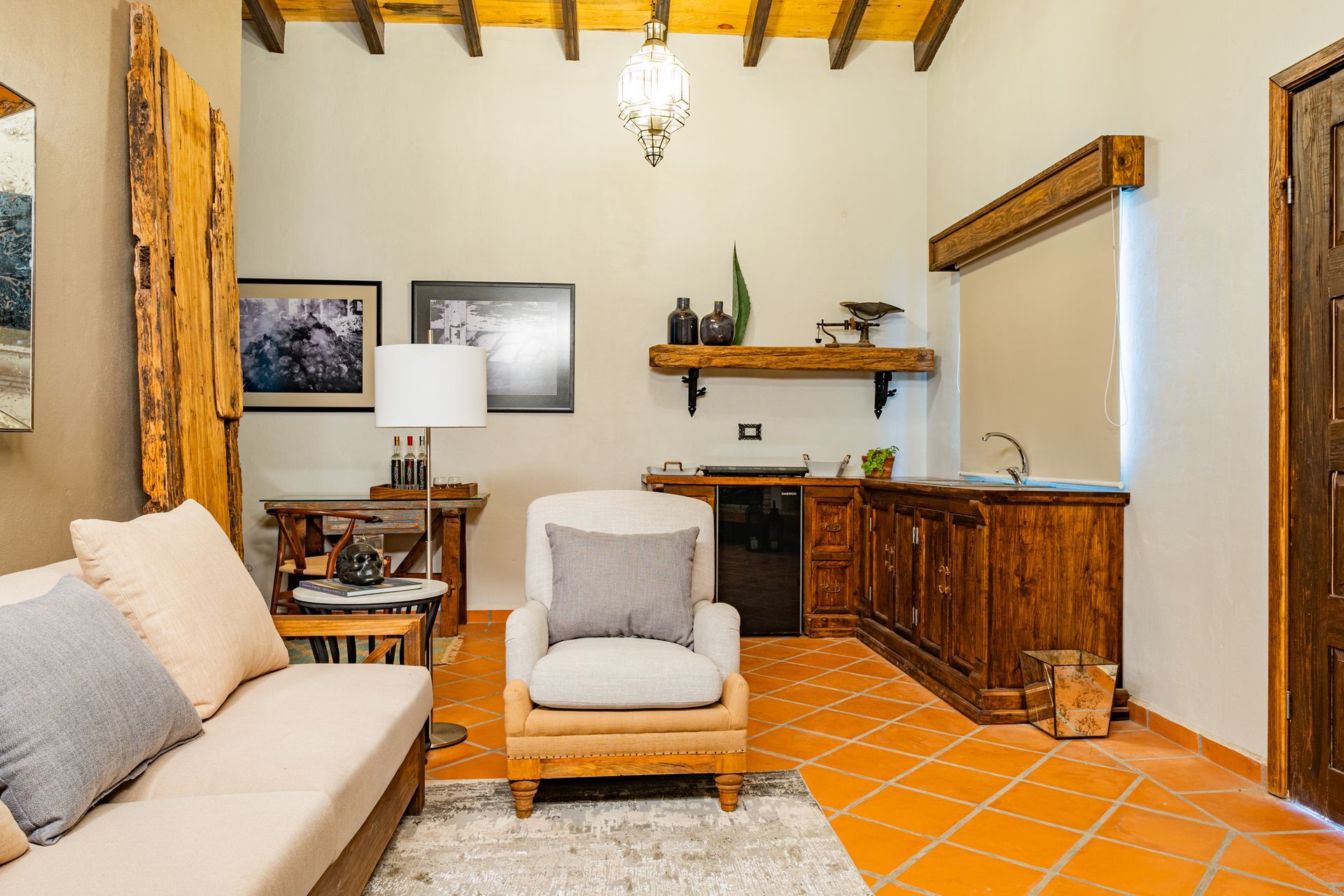Habitación acogedora con sofá, sillón y barra de madera; tonos tierra.