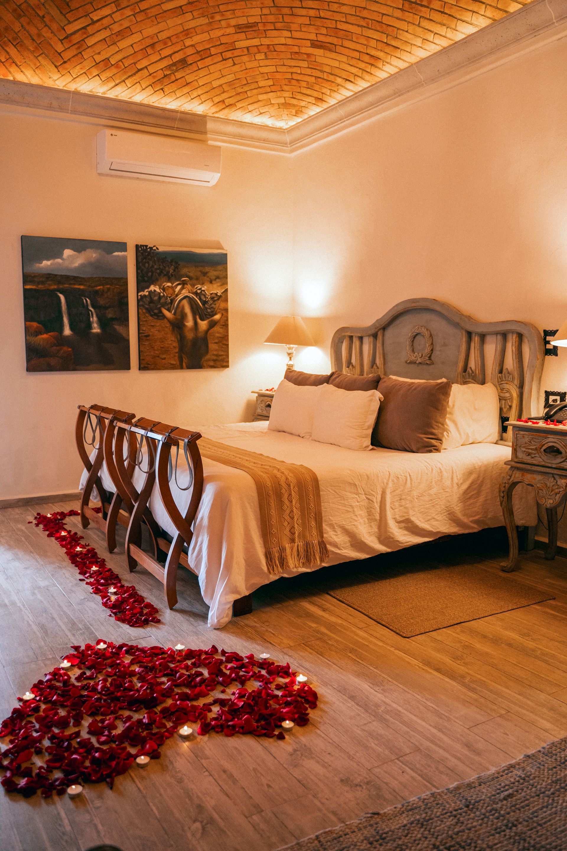 Dormitorio romántico con pétalos de rosa dispuestos en forma de corazón en el suelo frente a la cama.