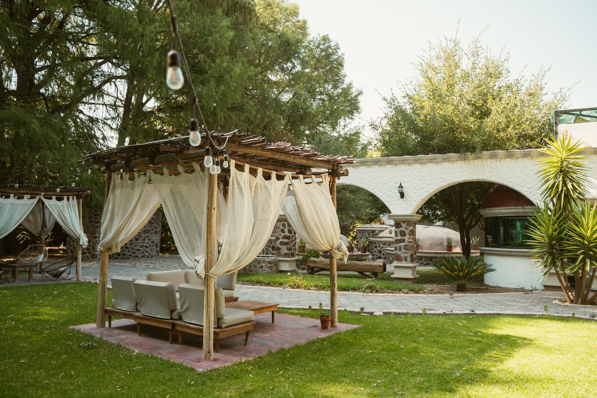 Outdoor seating area with draped canopies, in a grassy setting.