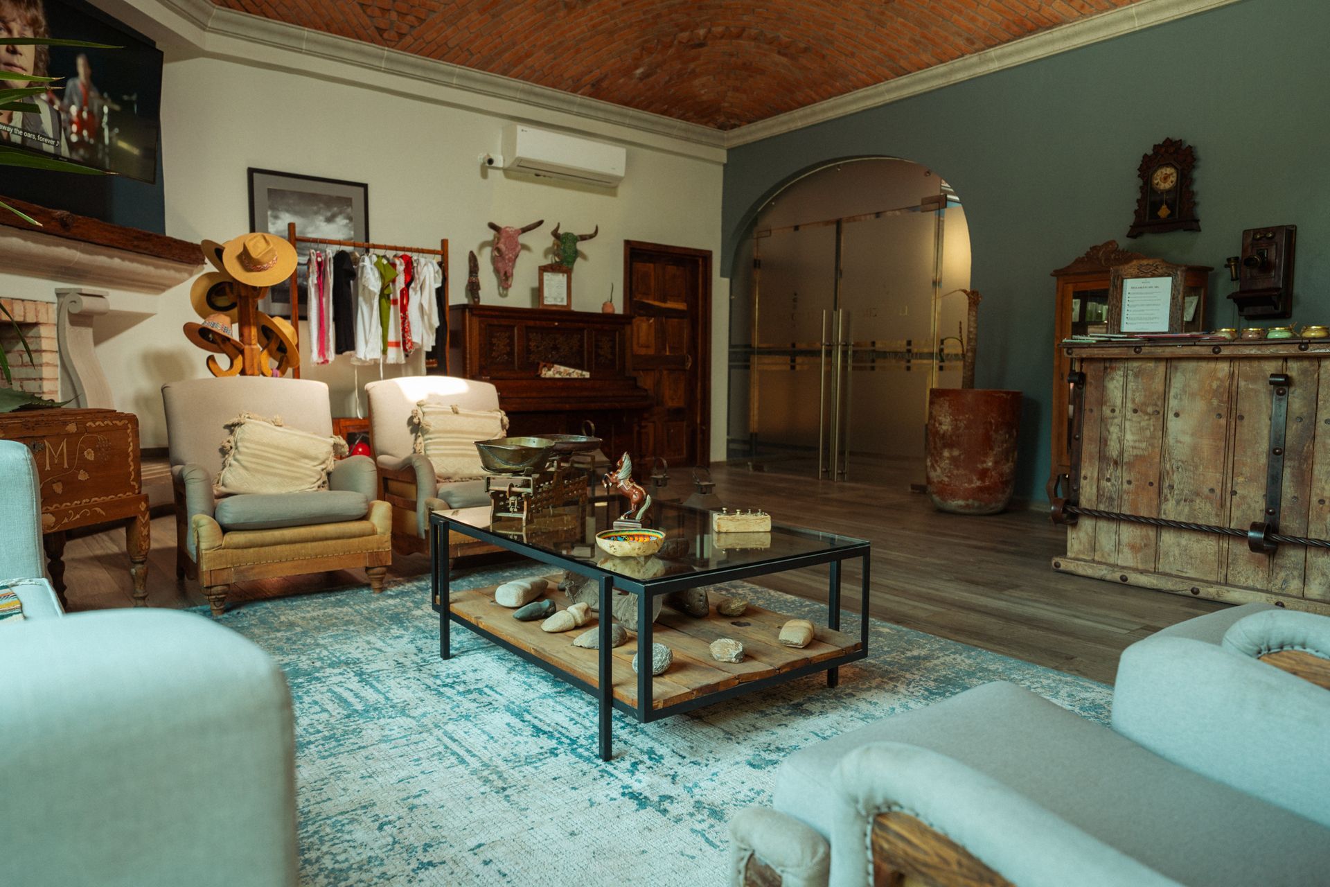 Salón con muebles antiguos, un piano de madera oscura y una alfombra.
