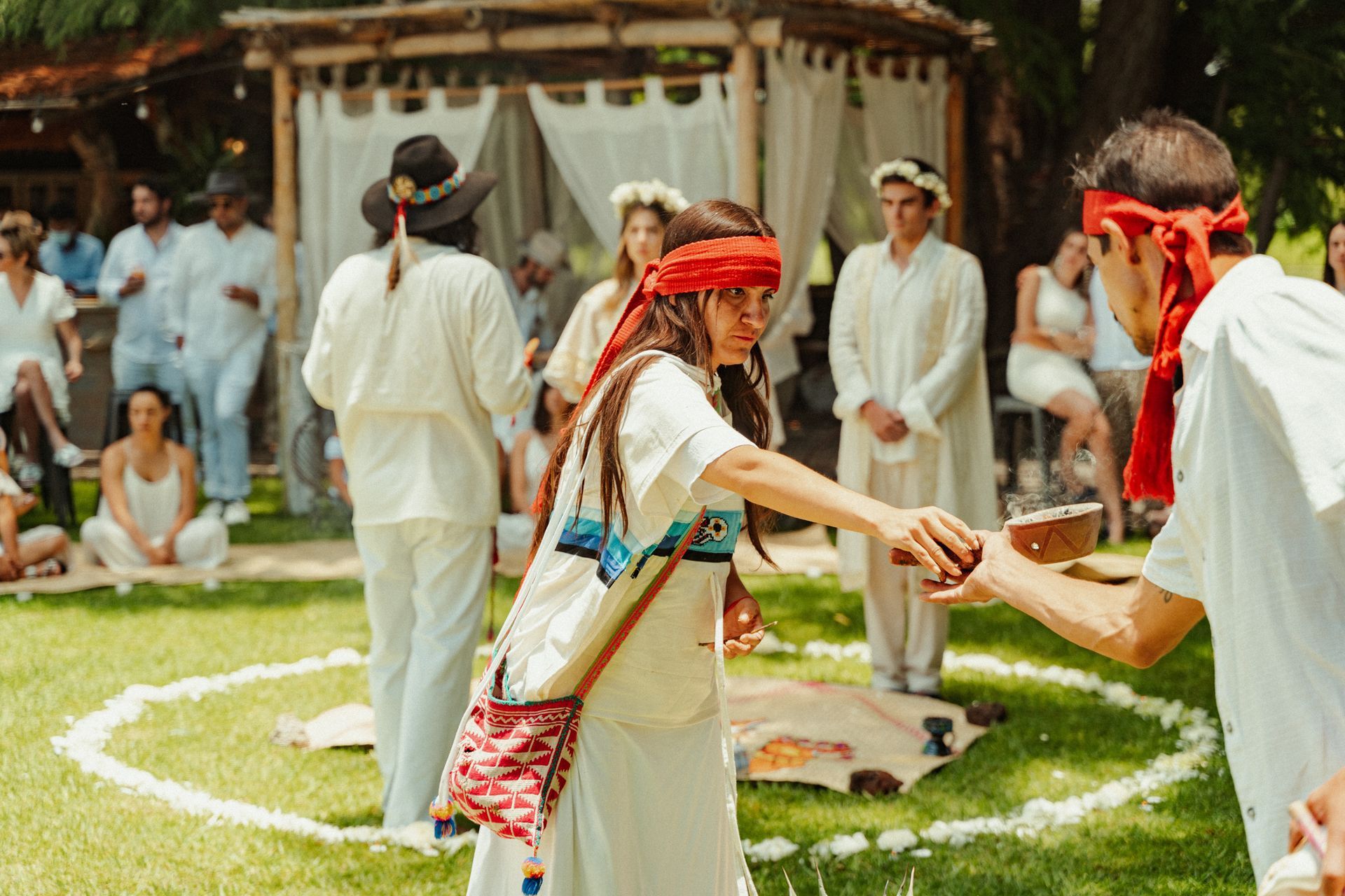 Personas vestidas con túnicas blancas participan en una ceremonia al aire libre.
