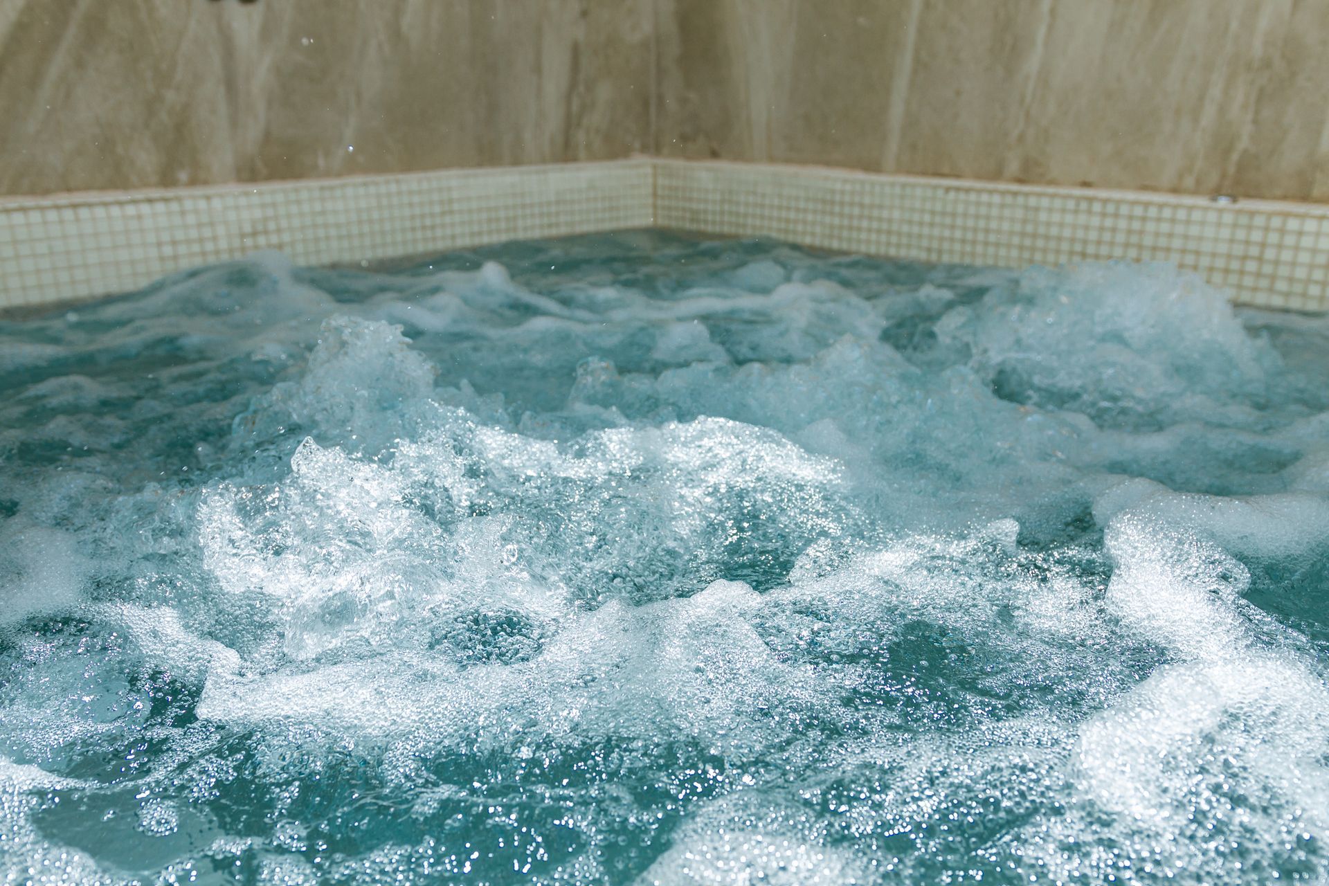Agua turquesa burbujeante en un jacuzzi de esquina revestido de azulejos.