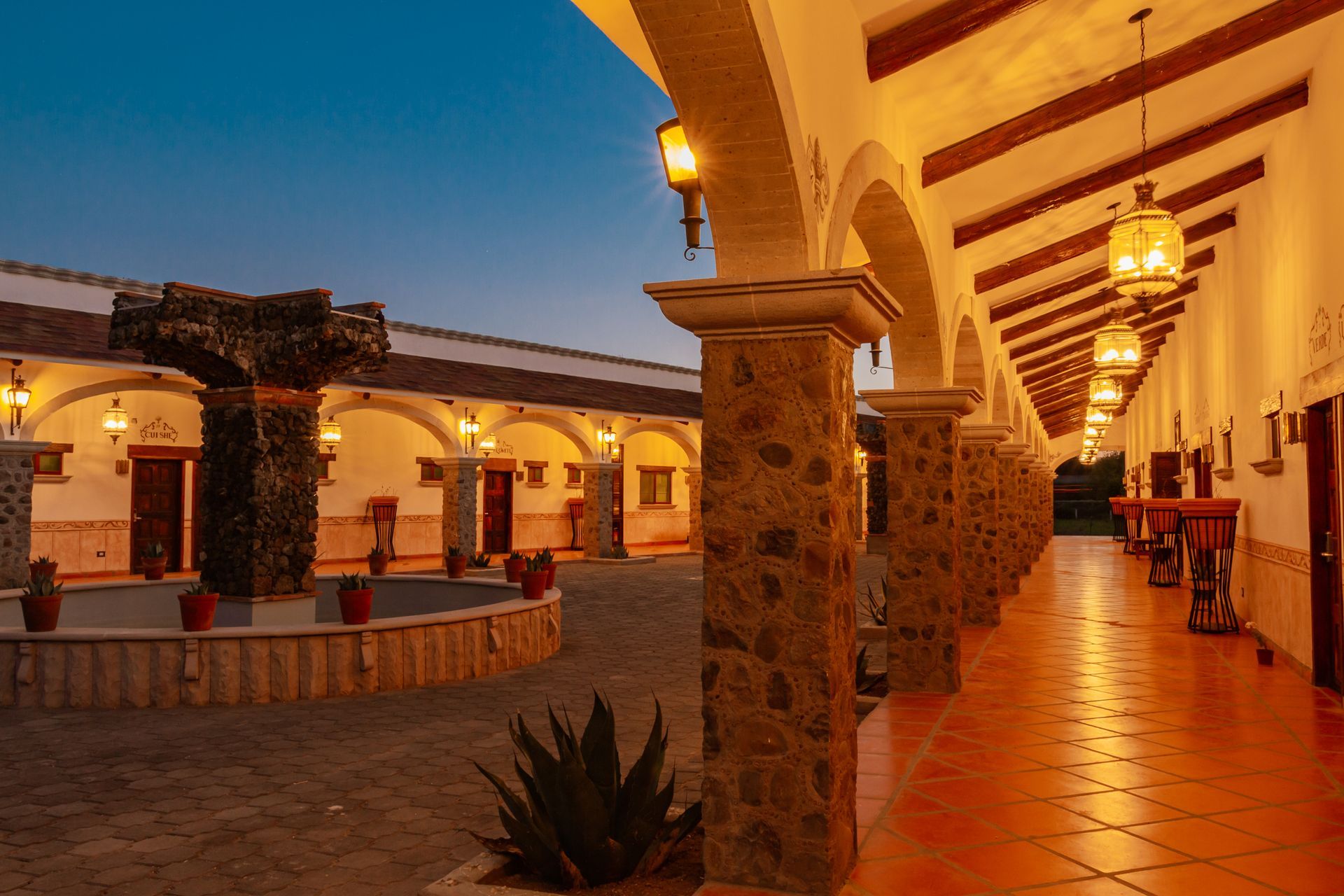 Courtyard with arches, stone columns, terracotta tiled floors, and decorative lanterns.