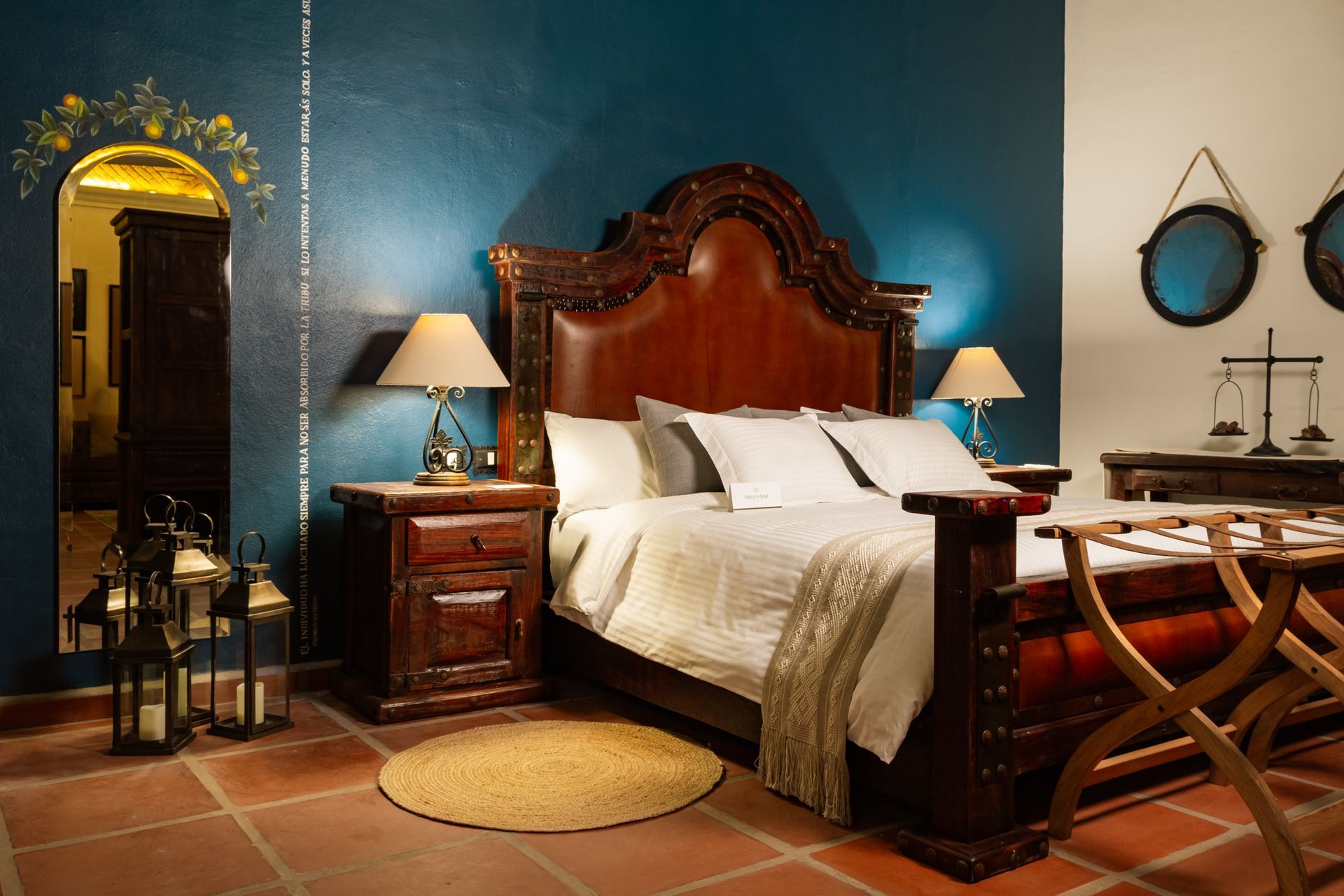 Ornate bedroom with a dark wood bed, teal wall, and terracotta floor.