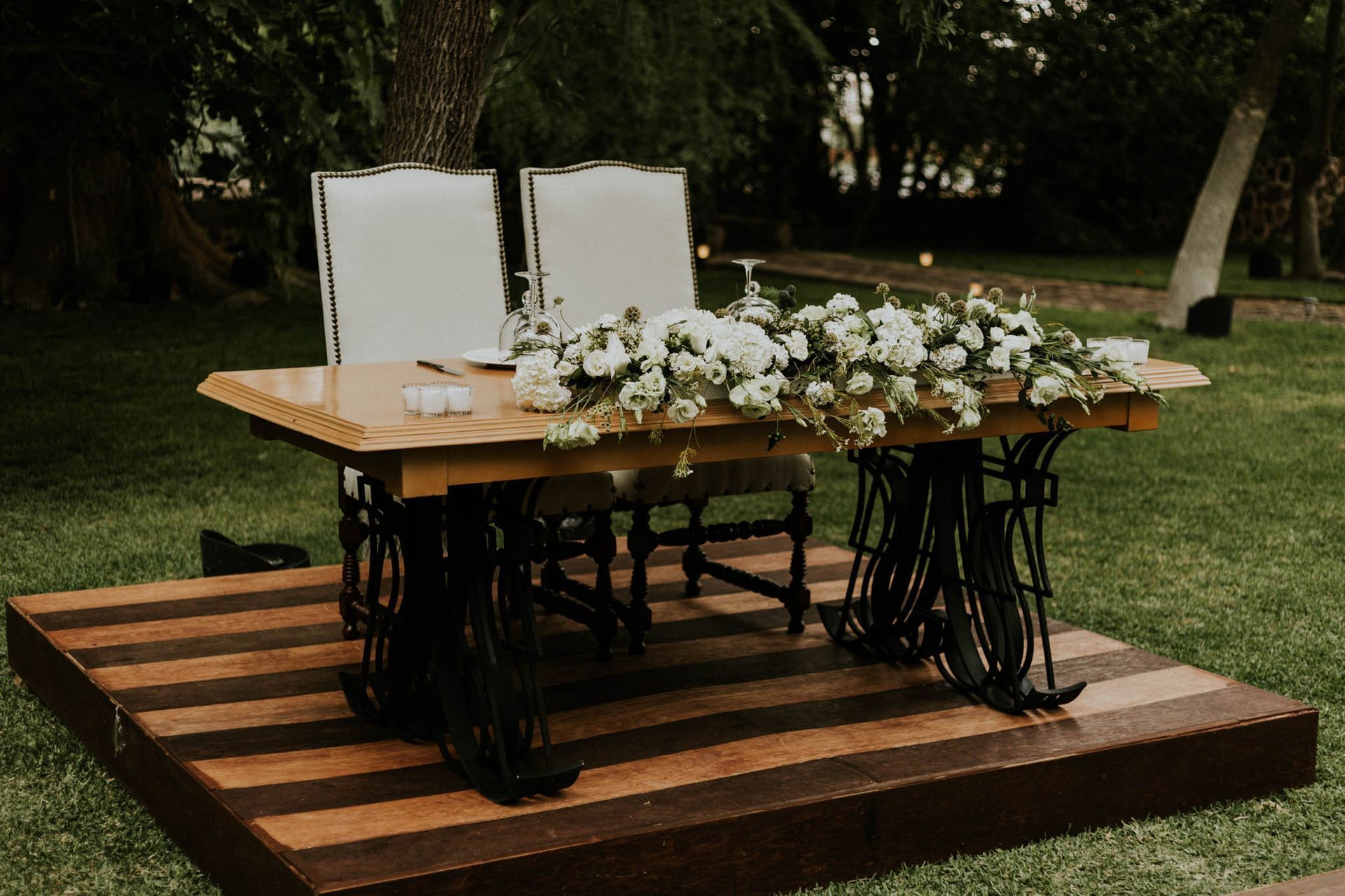 Wooden table with floral arrangement on a platform, supported by black sewing machine bases.
