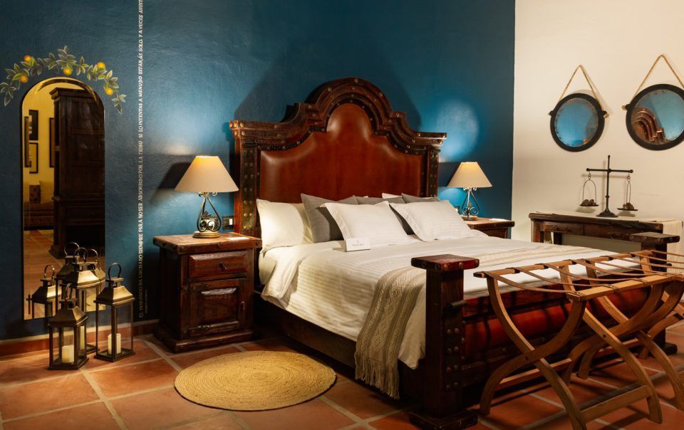 Elegant bedroom with a dark wooden bed, blue wall, round rug, and side tables.