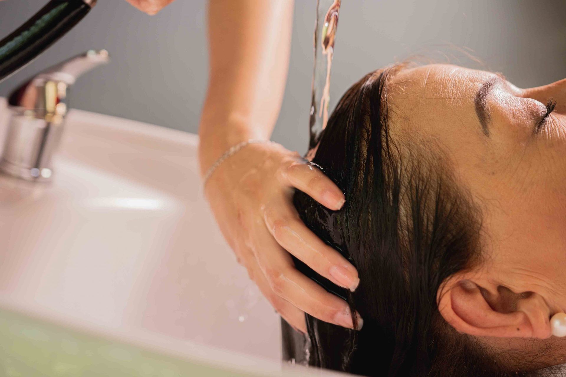 Enjuagarse el cabello en el lavabo de una peluquería. La cabeza de la persona está inclinada hacia atrás.