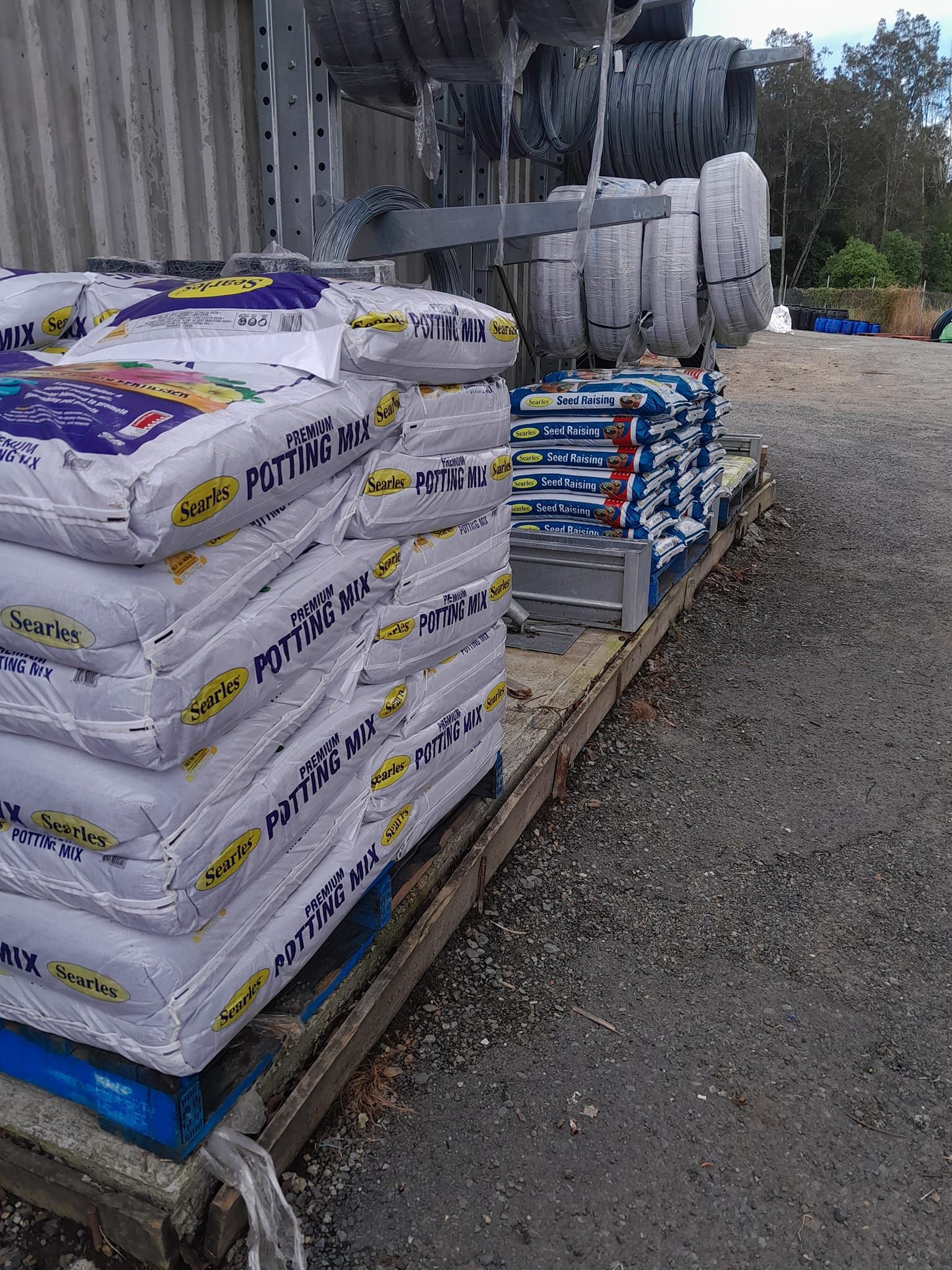 A Pile of soil bags, hoses and cables rolled up and hanging from a metals shelf outside — Farm and Home in Nabiac, NSW