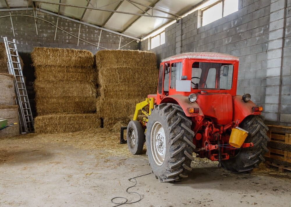 A Red Tractor is Parked in a Barn Next to Bales of Hay — Farm and Home in Nabiac, NSW