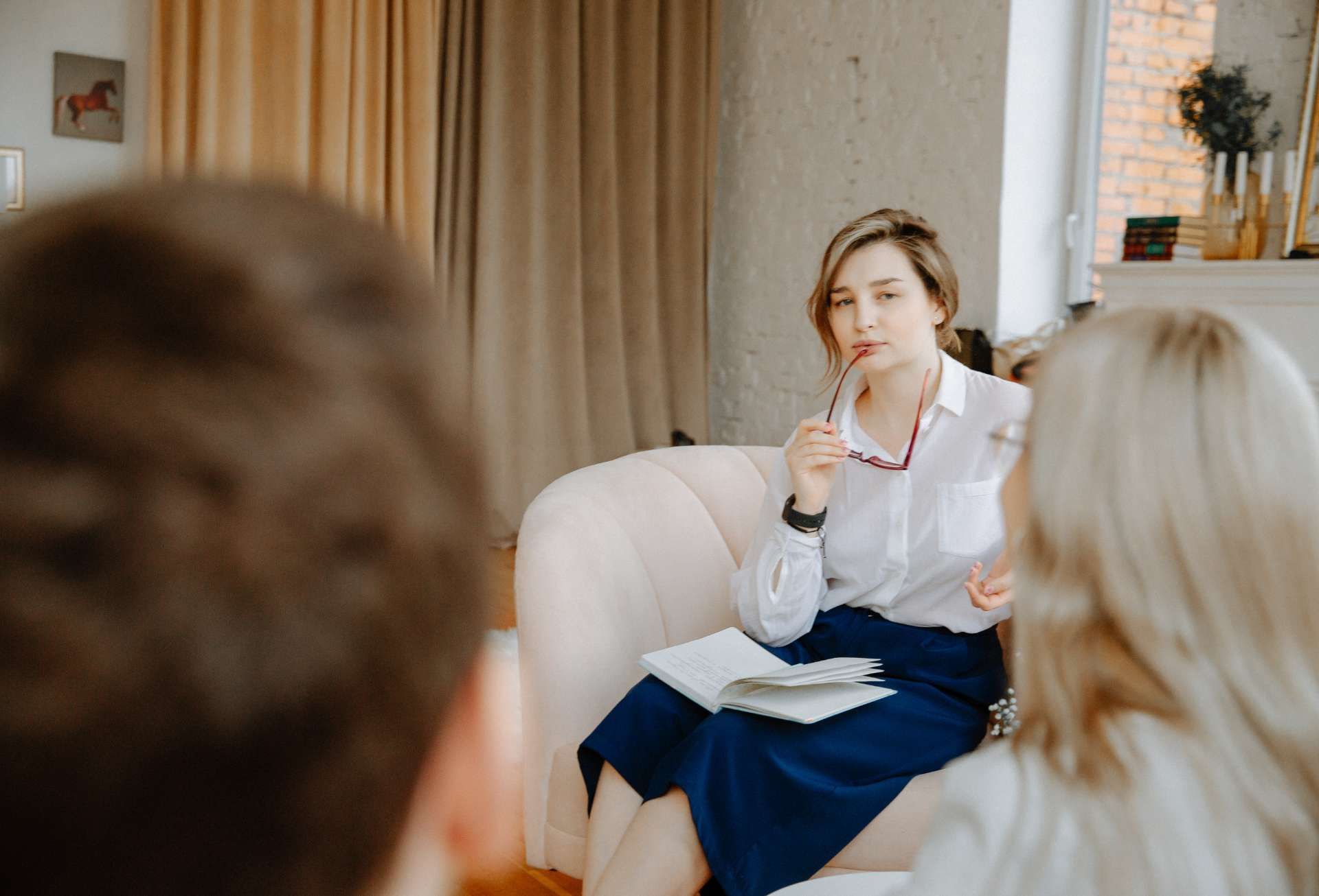 A woman with glasses is listening to a couple talk
