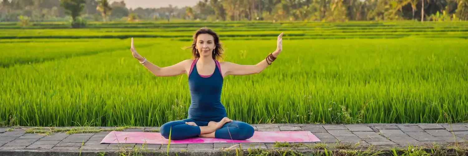 A woman is practicing yoga in a green field