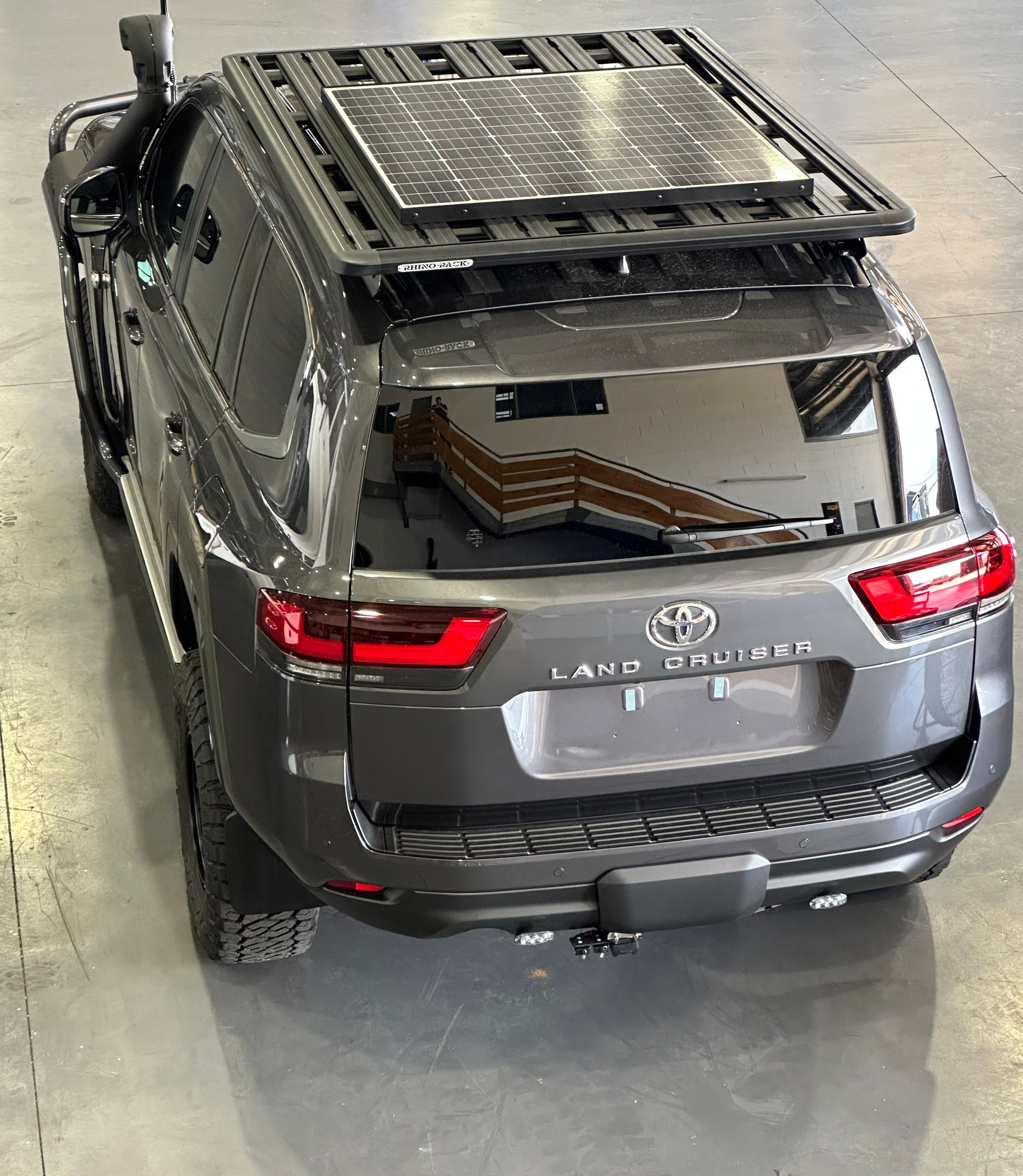 Gray SUV with a roof rack, parked indoors in a garage or showroom, rear view.  — Outback Auto NT in Berrimah, NT