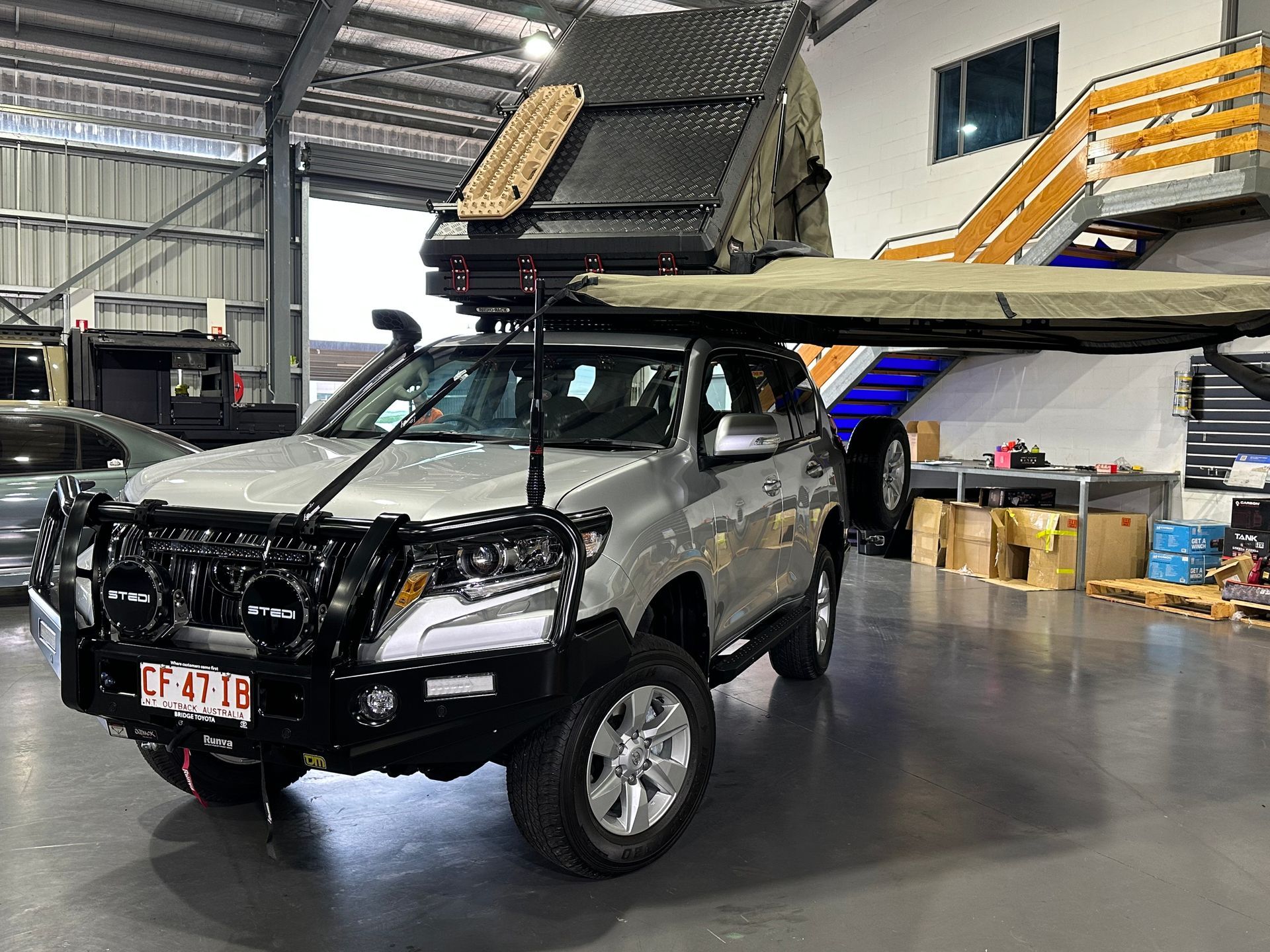 Silver off-road SUV with rooftop camper setup in a garage, front view. — Outback Auto NT in Berrimah, NT
