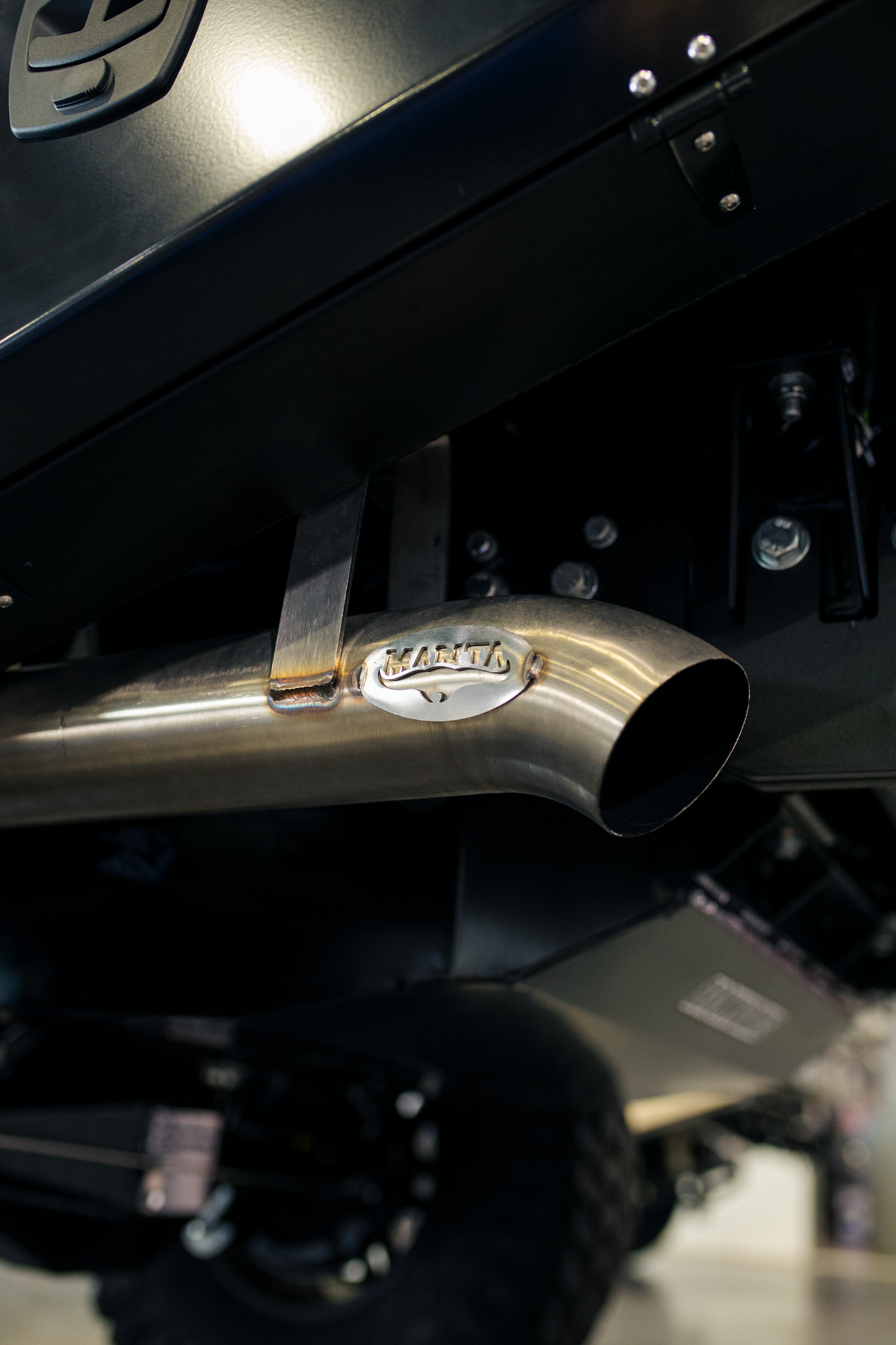 Close-up of a chrome exhaust pipe on a lifted vehicle, with off-road tire in the background  — Outback Auto NT in Berrimah, NT