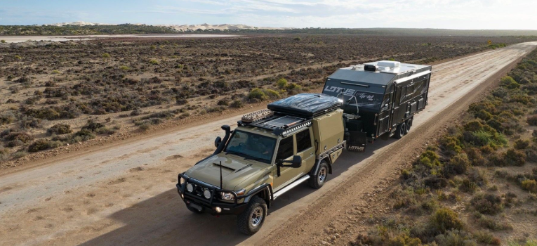 4WD towing a caravan along a remote outback road.