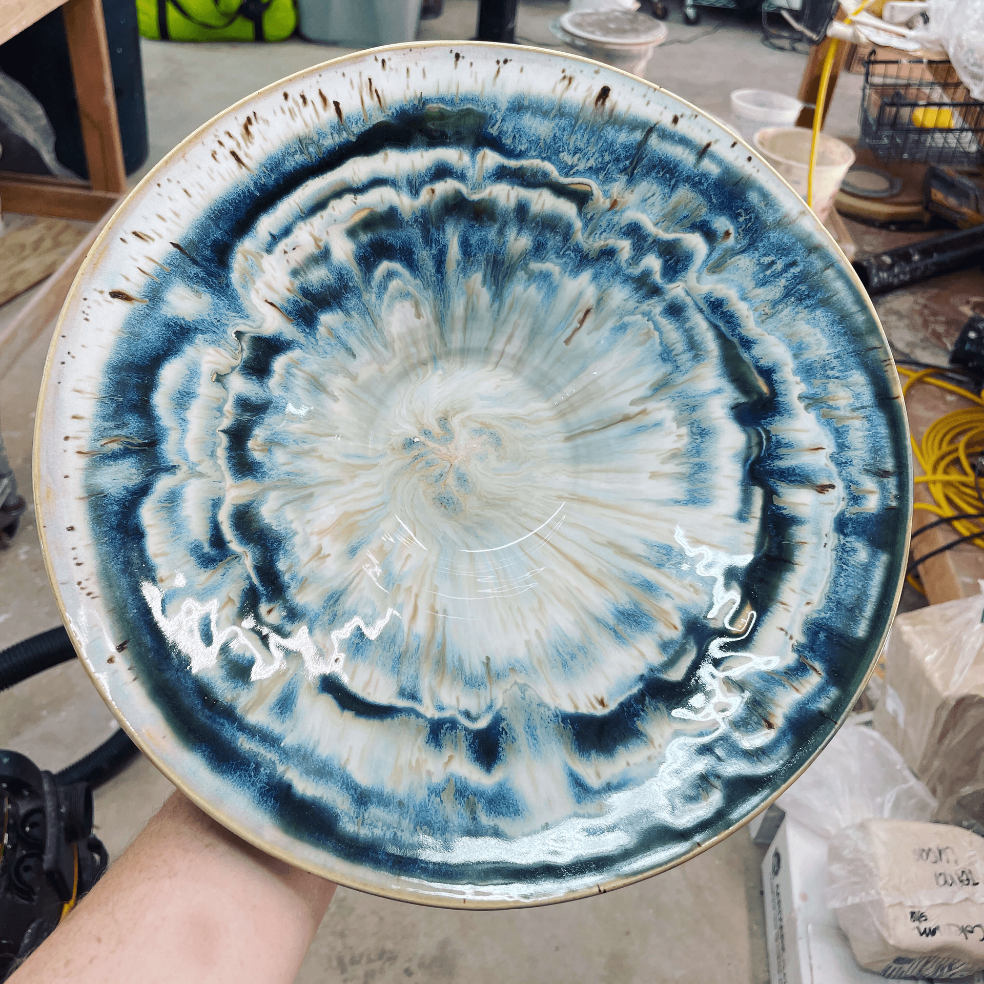 a large dinner platter in shades of blue, white, and grey held up by a hand to show the colors.