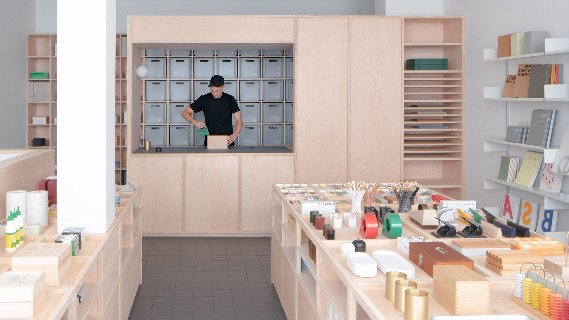 Small modern shop interior with a person behind the counter and shelves of goods on the right.