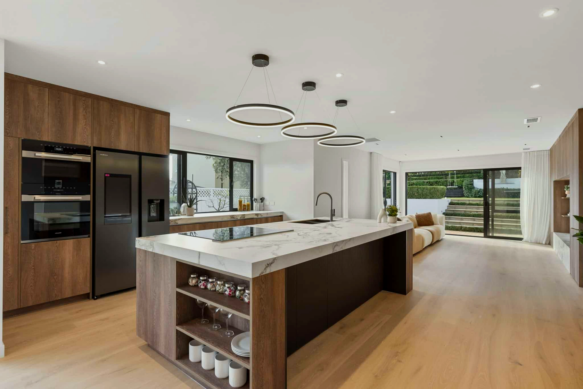 Modern kitchen with wood cabinetry, marble island, and open to living area.